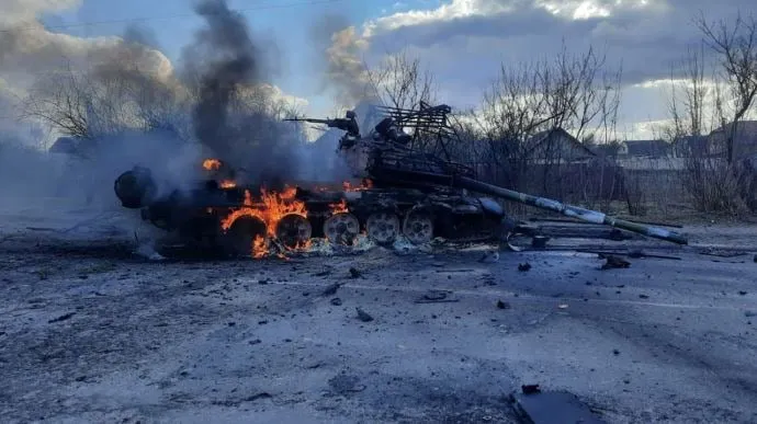 A Russian tank, with its distinctive anti-missile cages, burns in Ukraine.</body></html>